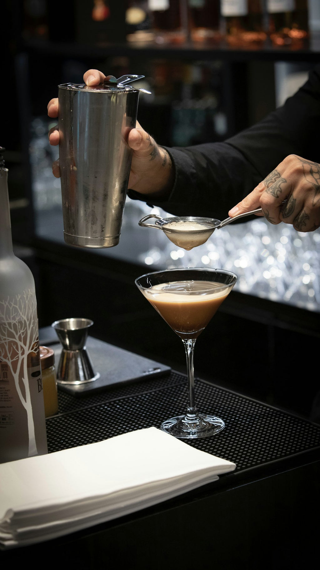 Bartender using a Hawthorne strainer to strain a cocktail — included in the Japanese leather bar roll