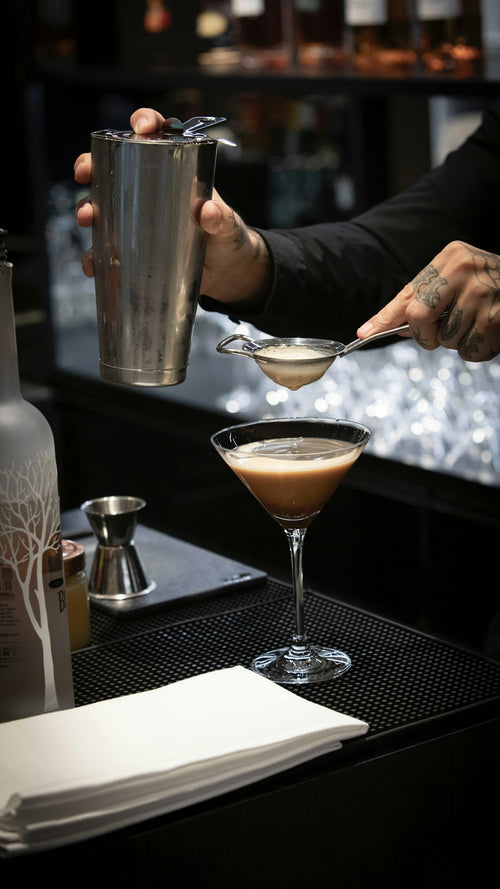 Bartender using a Hawthorne strainer to strain a cocktail — included in the Japanese leather bar roll